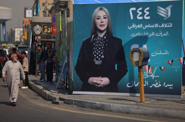 Iraqis walk past electoral billboards in central Baghdad on October 19, 2025, ahead of Iraq's parliamentary elections on November 11. (Photo by AHMAD AL-RUBAYE / AFP)