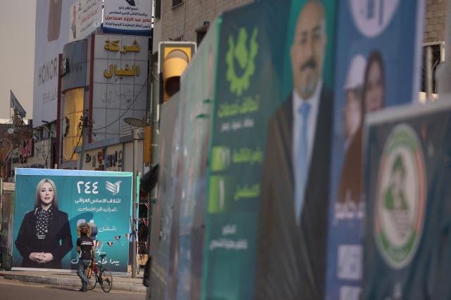 A Iraqi man walks past electoral billboards in central Baghdad on October 19, 2025, ahead of Iraq's parliamentary elections on November 11. (Photo by AHMAD AL-RUBAYE / AFP)