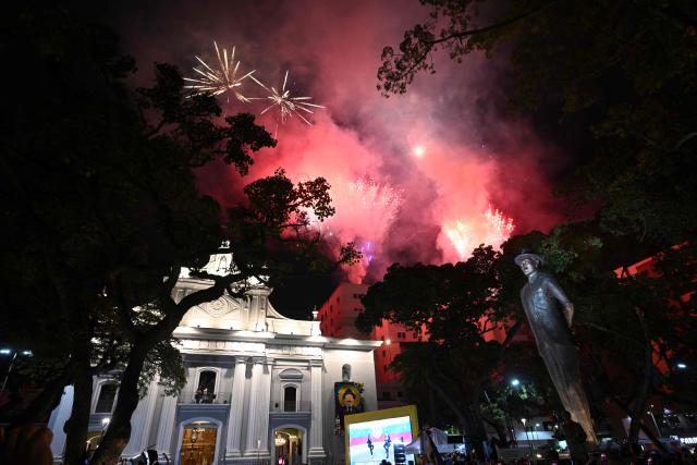 Fireworks explode above the statue of Jose Gregorio Hernandez during his canonization ceremony o at the Nuestra Senora de la Candelaria church in Caracas on October 18, 2025. (Photo by Federico PARRA / AFP)