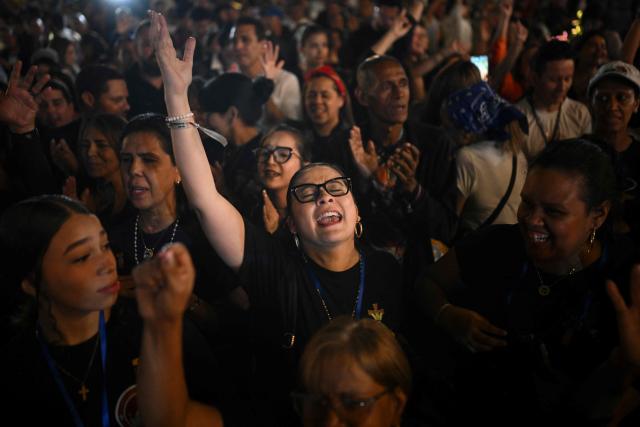 Catholic faithfuls sing while gathering at La Candelaria Square to attend the canonization ceremony of Venezuelan doctor Jose Gregorio Hernandez and Venezuelan Sister Maria Rendiles in Caracas on October 19, 2025. (Photo by Federico PARRA / AFP)