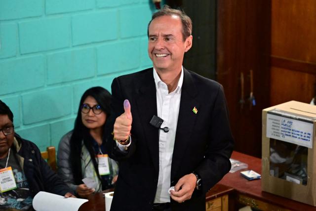 Bolivia's former president and presidential candidate for the Freedom and Democracy (Libre) alliance, Jorge "Tuto" Quiroga, shows his ink-stained thumb after casting his vote during the presidential runoff election in La Paz, Bolivia, on October 19, 2025. Bolivians head to the polls to choose between right-wing candidates Jorge 'Tuto' Quiroga and Senator Rodrigo Paz, both promising change as the country of some 12 million people sees the end of two decades of socialist rule. (Photo by MARTIN BERNETTI / AFP)