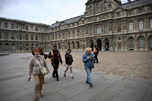 Security staff aske people to leave a courtyard of the Louvre after the announcement the museum will remain closed for a second day running after thieves stole crown jewels from the museum in Paris a day earlier, in Paris on October 20, 2025. (Photo by JULIEN DE ROSA / AFP)