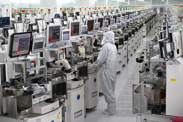 A technician works on chip processing equipment at a semiconductor manufacturing plant in Suqian, in eastern China's Jiangsu province on October 20, 2025. (Photo by Pedro PARDO / AFP) / China OUT