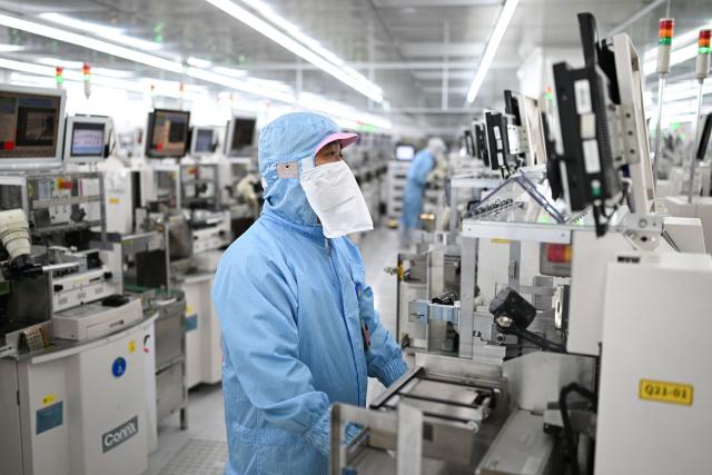 Technicians work on chip processing equipment at a semiconductor manufacturing plant in Suqian, in eastern China's Jiangsu province on October 20, 2025. (Photo by Pedro PARDO / AFP) / China OUT