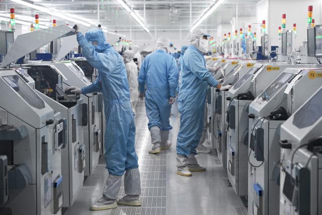 Technicians work on chip processing equipment at a semiconductor manufacturing plant in Suqian, in eastern China's Jiangsu province on October 20, 2025. (Photo by Pedro PARDO / AFP) / China OUT