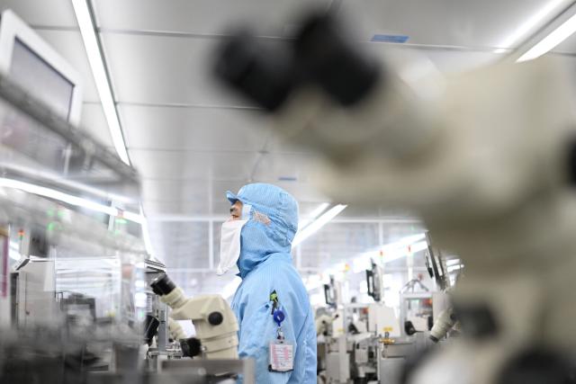 A technician works on chip processing equipment at a semiconductor manufacturing plant in Suqian, in eastern China's Jiangsu province on October 20, 2025. (Photo by Pedro PARDO / AFP) / China OUT