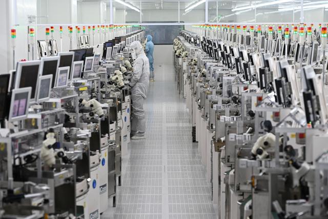 Technicians work on chip processing equipment at a semiconductor manufacturing plant in Suqian, in eastern China's Jiangsu province on October 20, 2025. (Photo by Pedro PARDO / AFP) / China OUT