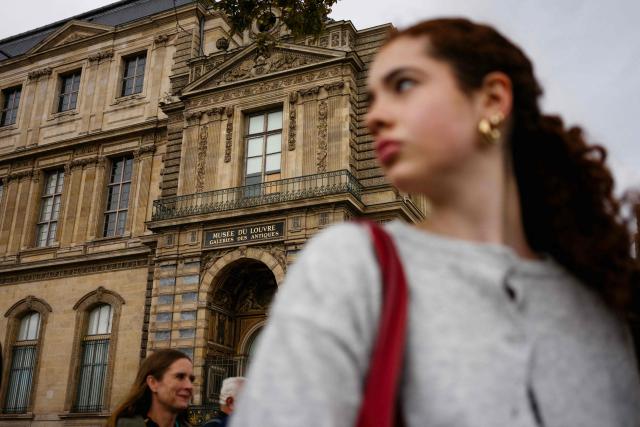 Pedestrians pass in front of the window of the Louvre Museum, through which the thieves entered to steal priceless jewels on the second day of the museum's closure after the theft, in Paris on October 20, 2025. (Photo by Dimitar DILKOFF / AFP)