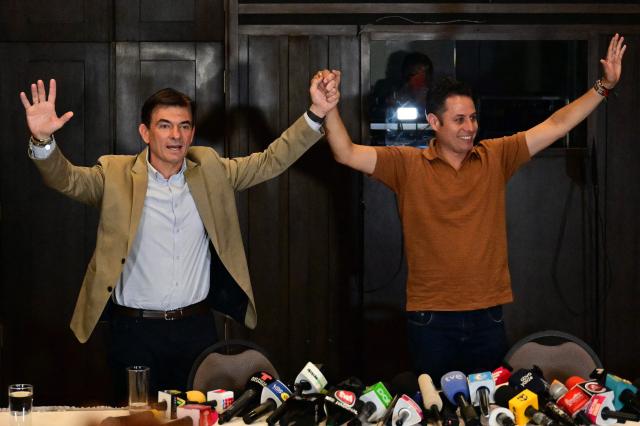 Bolivia's president-and vice-president elect Rodrigo Paz and Edman Lara, of the Christian Democratic Party (PDC), wave during a press conference a day after the presidential election runoff in La Paz, on October 20, 2025. Bolivians on the eve elected pro-business center-right senator Paz as their new president, ending two decades of socialist rule that have left the South American nation deep in economic crisis. (Photo by MARTIN BERNETTI / AFP)