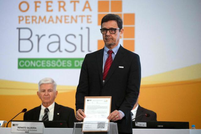 (FILES) Petrobras Exploration Executive Manager Jonilton Pessoa places his bid to explore the Amazon basin during an oil blocks auction by Brazil's Oil and Gas Regulatory Agency (ANP), in Rio de Janeiro, Brazil, on June 17, 2025. Just days before the COP30 climate summit in Brazil, Petrobras announced on October 20, 2025, that it had received authorization from environmental agency Ibama to begin oil drilling 500 km from the mouth of the Amazon River—a move that has sparked tensions between President Lula’s government and environmentalists. (Photo by Mauro PIMENTEL / AFP)