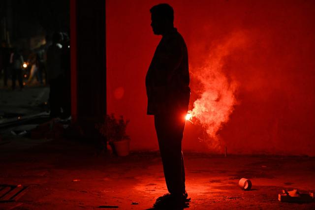 A man holds a firecracker during the Diwali, a Hindu festival of lights, in Bengaluru on October 20, 2025. (Photo by Idrees MOHAMMED / AFP)