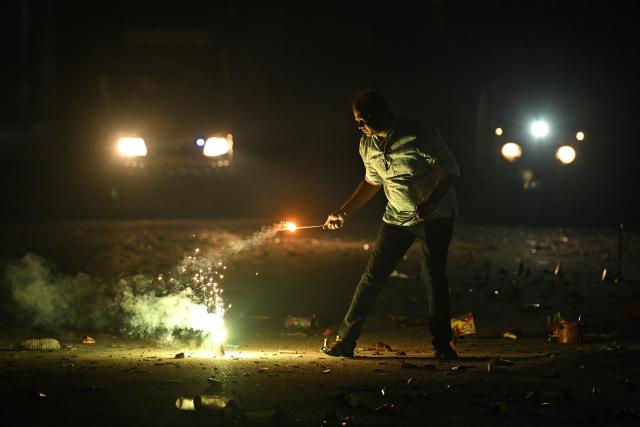 A man lights a firecracker during the Diwali, a Hindu festival of lights, in Bengaluru on October 20, 2025. (Photo by Idrees MOHAMMED / AFP)