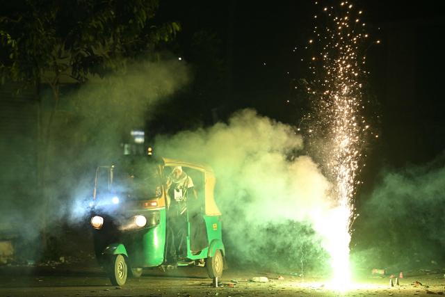 A rickshaw passes by firecrackers during the Diwali, a Hindu festival of lights, in Bengaluru on October 20, 2025. (Photo by Idrees MOHAMMED / AFP)