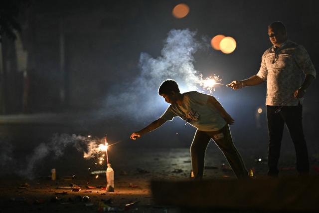 People light firecrackers during the Diwali, the Hindu festival of lights, in Bengaluru on October 20, 2025. (Photo by Idrees MOHAMMED / AFP)