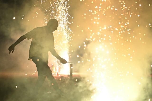A man lights a firecracker during the Diwali, the Hindu festival of lights, in Bengaluru on October 20, 2025. (Photo by Idrees MOHAMMED / AFP)