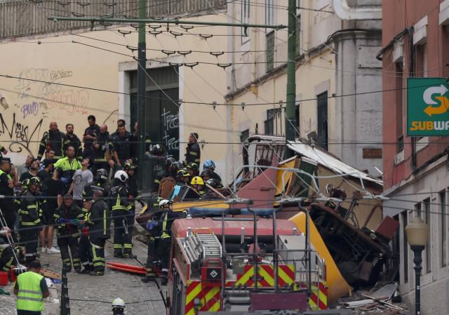 (FILES) Police and firefighters work on the site of the Gloria funicular railway accident in Lisbon, on September 3, 2025. An official inquiry called Monday for all Lisbon cable cars to be kept out of service for urgent modifications after a deadly crash in September that it blamed on a defective cable. The September 3 crash when the funicular came off the rails and hurtled into a building left 16 dead. The official inquiry's preliminary report said Lisbon's cable cars cannot resume operating until they can guarantee they have braking systems "capable of immobilizing the cabins in the event of a cable break." (Photo by PATRICIA DE MELO MOREIRA / AFP)