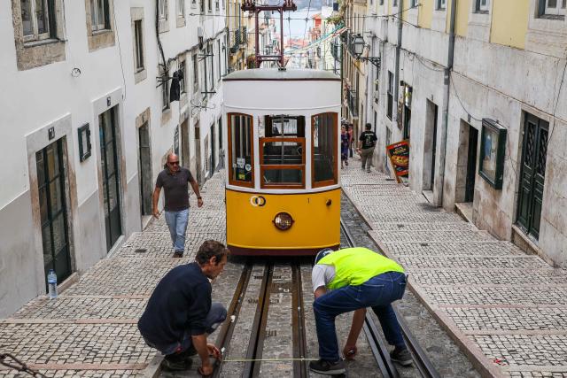 (FILES) Carris technicians perform tests on a Bica funicular car, closed temporarily after the Gloria funicular accident in Lisbon on September 10, 2025. An official inquiry called Monday for all Lisbon cable cars to be kept out of service for urgent modifications after a deadly crash in September that it blamed on a defective cable. The September 3 crash when the funicular came off the rails and hurtled into a building left 16 dead. The official inquiry's preliminary report said Lisbon's cable cars cannot resume operating until they can guarantee they have braking systems "capable of immobilizing the cabins in the event of a cable break." (Photo by PATRICIA DE MELO MOREIRA / AFP)
