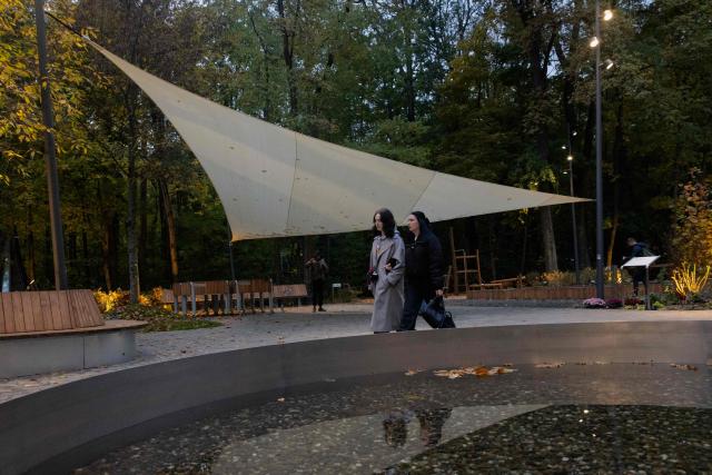 People walk through a Therapeutic Garden in Kyiv, on October 20, 2025, amid the Russian invasion of Ukraine. Developed by artist and lighting designer Mykola Kabluka the Therapeutic Garden was created to assist in the recovery and emotional support of veterans and general public with the aim to restore health through movement in contact with nature. (Photo by Tetiana DZHAFAROVA / AFP)