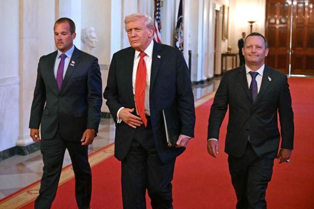 US President Donald Trump arrives, flanked by LSU Shreveport coach Brad Neffendorf (L) and Louisiana State University (LSU) coach Jay Johnson (R), to greet the college baseball teams of Louisiana State University (LSU) and LSU Shreveport, winners of this year College World Series and the National Championships, respectively, at the White House in Washington, DC, on October 20, 2025. (Photo by SAUL LOEB / AFP)