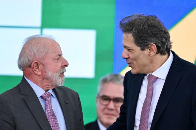 Brazil's President Luiz Inacio Lula da Silva (L) talks with Finance Minister Fernando Haddad during the launch of a home renovation program for low-income families at Planalto Palace in Brasilia on October 20, 2025. (Photo by Evaristo Sa / AFP)