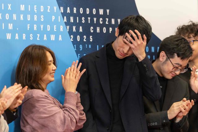 The winner the 19th International Chopin Piano Competition Eric Lu (C) reacts after the results were announced in Warsaw on October 21, 2025 as other competitors Zitong Wang (L) from China, William Yang (2R) from USA and Tianyou Li from China applaud him. (Photo by Wojtek RADWANSKI / AFP)
