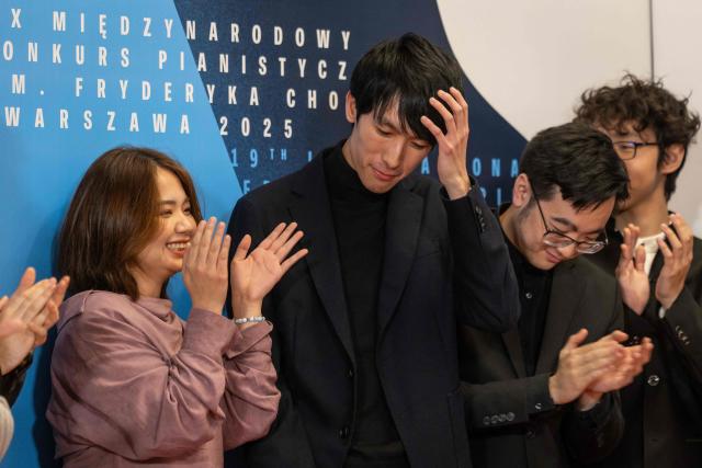 The winner the 19th International Chopin Piano Competition Eric Lu (C) reacts after the results were announced in Warsaw on October 21, 2025 as other competitors Zitong Wang (L) from China, William Yang (2R) from USA and Tianyou Li from China applaud him. (Photo by Wojtek RADWANSKI / AFP)