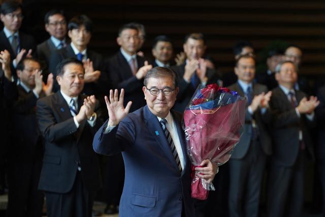 Japan's outgoing Prime Minister Shigeru Ishiba leaves after receiving flowers and applause at the prime minister's office on his final day as the Japanese leader in Tokyo on October 21, 2025.  (Photo by Kazuhiro NOGI / AFP)