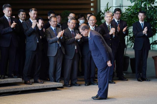 Japan's outgoing Prime Minister Shigeru Ishiba (C) bows as he leaves the prime minister's office on his final day as the Japanese leader in Tokyo on October 21, 2025.  (Photo by Kazuhiro NOGI / AFP)