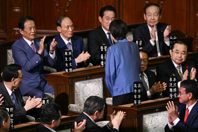 Liberal Democratic Party (LDP) President Sanae Takaichi (C, back facing camera)  acknowledges former prime minister Yoshihide Suga (top 2nd L) after she was selected as Japan's new prime minister during an extraordinary session of the lower house of parliament in Tokyo on October 21, 2025.  (Photo by Philip FONG / AFP)