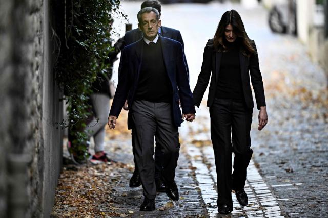 France's former president Nicolas Sarkozy (L), with his wife Carla Bruni-Sarkozy, leaves his residence to present himself to La Sante Prison for incarceration on a five-year prison sentence after being convicted of criminal conspiracy over a plan for late Libyan dictator Moamer Kadhafi to fund his 2007 electoral campaign, in Paris, on October 21, 2025. Nicolas Sarkozy, who has faced a flurry of legal woes since losing re-election in 2012, is to be jailed on October 21, 2025, over a scheme to acquire Libyan funding for his successful 2007 presidential run, becoming the first former head of a European Union country to serve time behind bars. The former French right-wing leader has appealed the verdict and denounced an "injustice". (Photo by JULIEN DE ROSA / AFP)