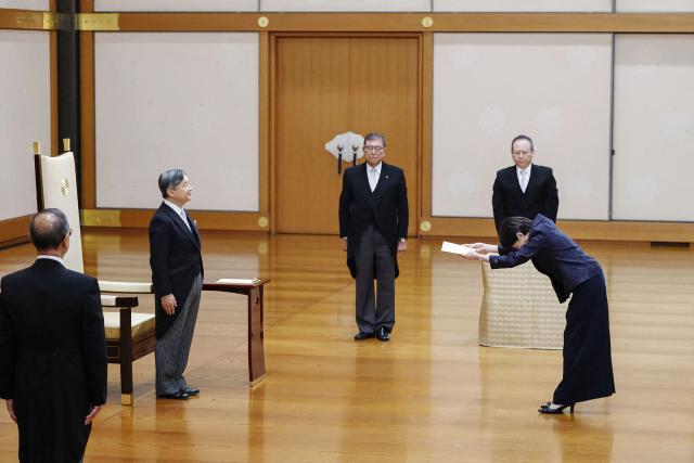 Japan's Emperor Naruhito (2nd L) stands in front of new Prime Minister Sanae Takaichi (R) while former prime minister Shigeru Ishiba (C) looks on during Takaichi's investiture ceremony at the Imperial Palace in Tokyo on October 21, 2025. (Photo by JAPAN POOL / JIJI PRESS / AFP) / Japan OUT