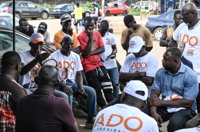 Supporters, wearing t-shirts bearing the portrait of Ivorian President Alassane Ouattara, and presidential candidate of the Rally of Houphouetists for Democracy and Peace (RHDP), campaign for the upcoming presidential election, in Abobo, northern suburb of Abidjan, on October 21, 2025. The presidential election in Ivory Coast will be held on October 25, 2025, (Photo by Sia KAMBOU / AFP)