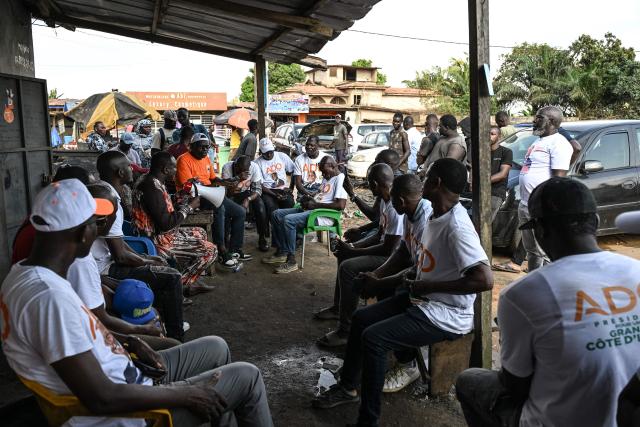 Supporters, wearing t-shirts bearing the portrait of Ivorian President Alassane Ouattara, and presidential candidate of the Rally of Houphouetists for Democracy and Peace (RHDP), campaign for the upcoming presidential election, in Abobo, northern suburb of Abidjan, on October 21, 2025. The presidential election in Ivory Coast will be held on October 25, 2025, (Photo by Sia KAMBOU / AFP)