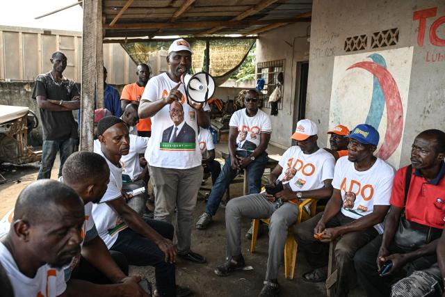 Supporters, wearing t-shirts bearing the portrait of Ivorian President Alassane Ouattara, and presidential candidate of the Rally of Houphouetists for Democracy and Peace (RHDP), campaign for the upcoming presidential election, in Abobo, northern suburb of Abidjan, on October 21, 2025. The presidential election in Ivory Coast will be held on October 25, 2025, (Photo by Sia KAMBOU / AFP)