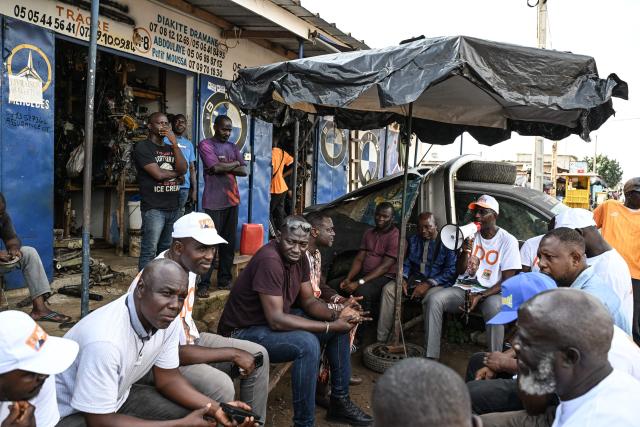 Supporters, wearing t-shirts bearing the portrait of Ivorian President Alassane Ouattara, and presidential candidate of the Rally of Houphouetists for Democracy and Peace (RHDP), campaign for the upcoming presidential election, in Abobo, northern suburb of Abidjan, on October 21, 2025. The presidential election in Ivory Coast will be held on October 25, 2025, (Photo by Sia KAMBOU / AFP)