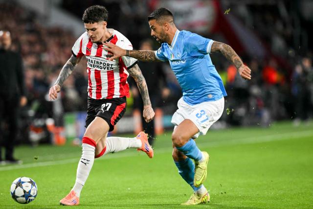 PSV Eindhoven's Romanian forward #27 Dennis Man (L) fights for the ball with Napoli's Italian defender #37 Leonardo Spinazzola during the UEFA Champions League, league phase football match between PSV Eindhoven and Napoli at the Philips Stadium, in Eindhoven, on October 21, 2025. (Photo by NICOLAS TUCAT / AFP)