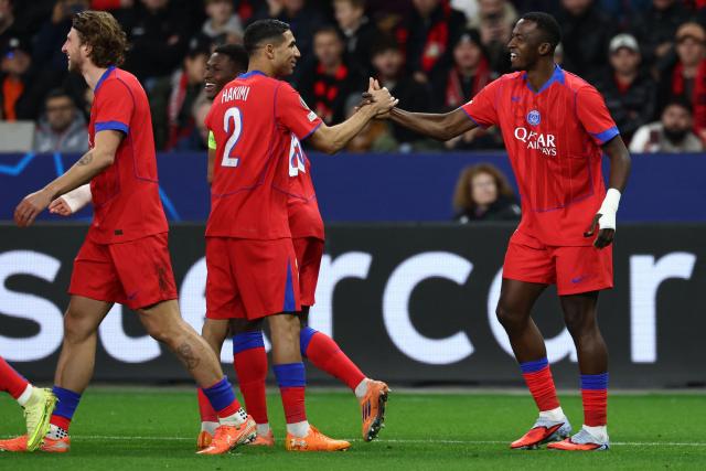Paris Saint-Germain's Ecuadoran defender #51 Willian Pacho (R) celebrates scoring the opening goal with his teammates including Paris Saint-Germain's Moroccan defender #02 Achraf Hakimi during the UEFA Champions League football match between Bayer 04 Leverkusen and Paris Saint-Germain (PSG) at the BayArena stadium in Leverkusen, western Germany on October 21, 2025. (Photo by FRANCK FIFE / AFP)