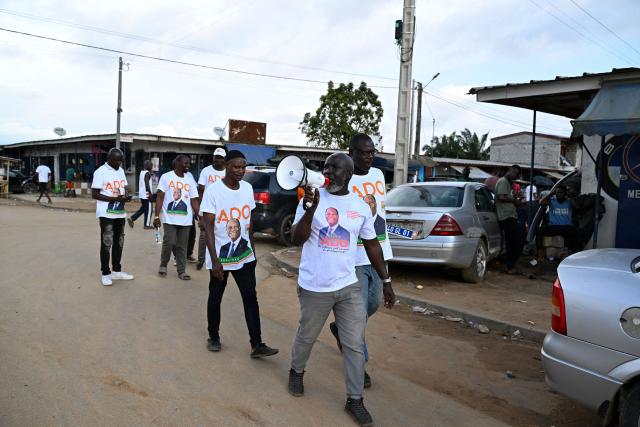 Supporters, wearing t-shirts bearing the portrait of Ivorian President Alassane Ouattara, and presidential candidate of the Rally of Houphouetists for Democracy and Peace (RHDP), campaign for the upcoming presidential election, in Abobo, northern suburb of Abidjan, on October 21, 2025. The presidential election in Ivory Coast will be held on October 25, 2025, (Photo by Sia KAMBOU / AFP)