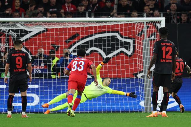 Paris Saint-Germain's French goalkeeper #30 Lucas Chevalier dives for the ball as Bayer Leverkusen's Spanish defender #20 Alejandro Grimaldo's (R) peanalt hits the post during the UEFA Champions League football match between Bayer 04 Leverkusen and Paris Saint-Germain (PSG) at the BayArena stadium in Leverkusen, western Germany on October 21, 2025. (Photo by FRANCK FIFE / AFP)