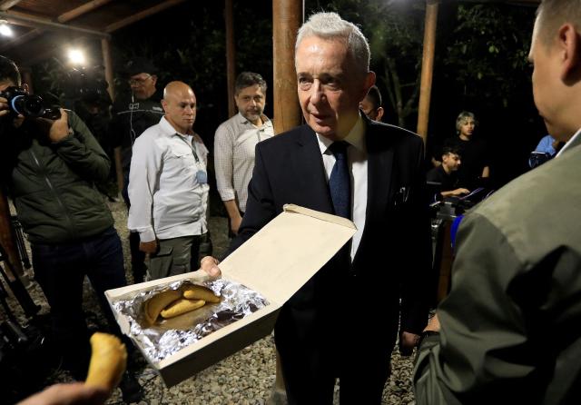 Former Colombian President Alvaro Uribe offers food to the media after a press conference in Rionegro, Antioquia department, Colombia on October 21, 2025. A Colombian court on Tuesday overturned the witness tampering conviction of influential ex-president Alvaro Uribe, who had been sentenced to 12 years' house arrest in a decision condemned by the US. (Photo by JAIME SALDARRIAGA / AFP)