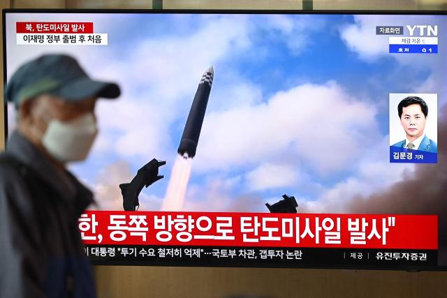 A man walks past a television screen showing a news broadcast with file footage of a North Korean missile test, at a train station in Seoul on October 22, 2025. North Korea fired at least one ballistic missile on October 22, Seoul's military said, its first such launch in months. (Photo by Jung Yeon-je / AFP)