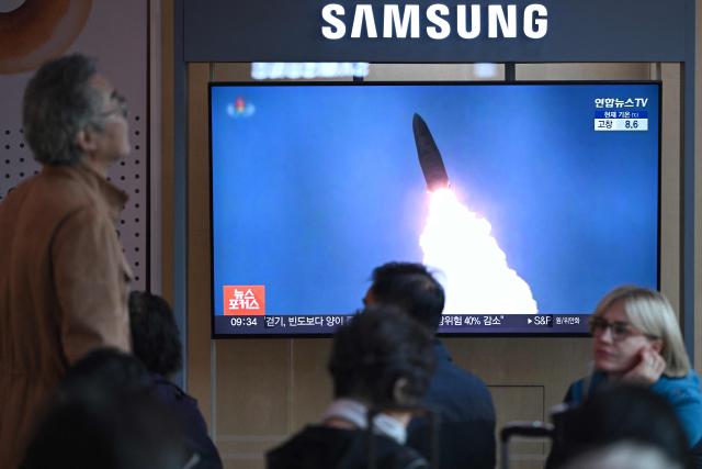 People sit in front of a television screen showing a news broadcast with file footage of a North Korean missile test, at a train station in Seoul on October 22, 2025. North Korea fired at least one ballistic missile on October 22, Seoul's military said, its first such launch in months. (Photo by Jung Yeon-je / AFP)
