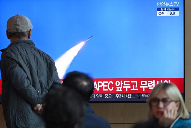 A man walks past a television screen showing a news broadcast with file footage of a North Korean missile test, at a train station in Seoul on October 22, 2025. North Korea fired at least one ballistic missile on October 22, Seoul's military said, its first such launch in months. (Photo by Jung Yeon-je / AFP)