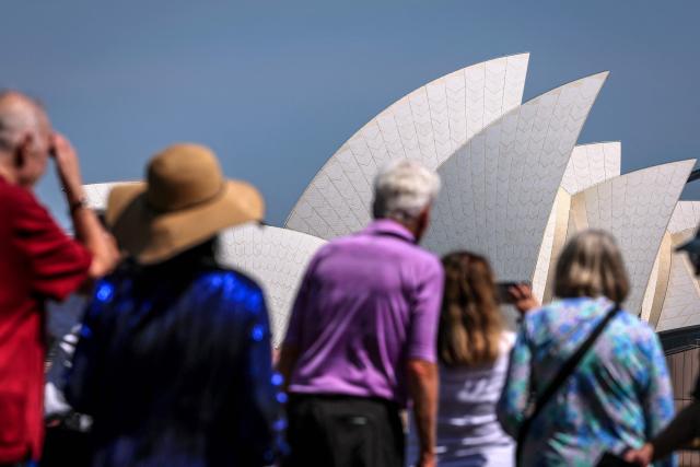 Tourists look across to the Sydney Opera House on a hot and windy spring day in Sydney on October 22, 2025. (Photo by DAVID GRAY / AFP)