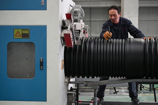 An employee works on the production line of polyethylene pipes at a factory in Suqian, in eastern China's Jiangsu province on October 21, 2025. (Photo by AFP) / China OUT