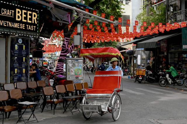 A cyclo driver waits for customers in front of a restaurant in Hanoi on October 22, 2025. (Photo by Nhac NGUYEN / AFP)