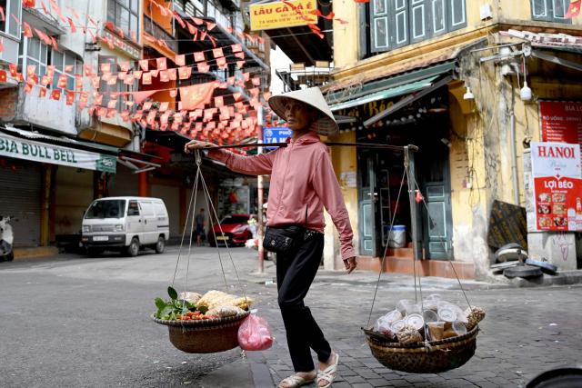 A street vendor carries food for sale in Hanoi on October 22, 2025. (Photo by Nhac NGUYEN / AFP)