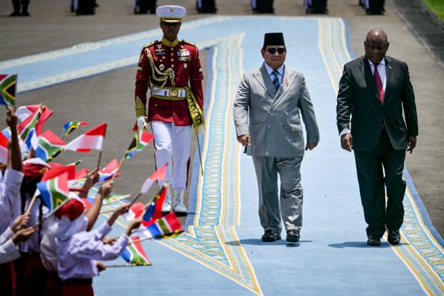 Indonesia’s President Prabowo Subianto (C) and South Africa’s President Cyril Ramaphosa (R) inspect an honour guard before their bilateral meeting at the presidential palace in Jakarta on October 22, 2025. (Photo by Bay ISMOYO / AFP)