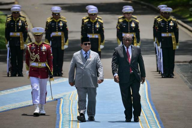 Indonesia’s President Prabowo Subianto (C) and South Africa’s President Cyril Ramaphosa (R) inspect an honour guard before their bilateral meeting at the presidential palace in Jakarta on October 22, 2025. (Photo by Bay ISMOYO / AFP)