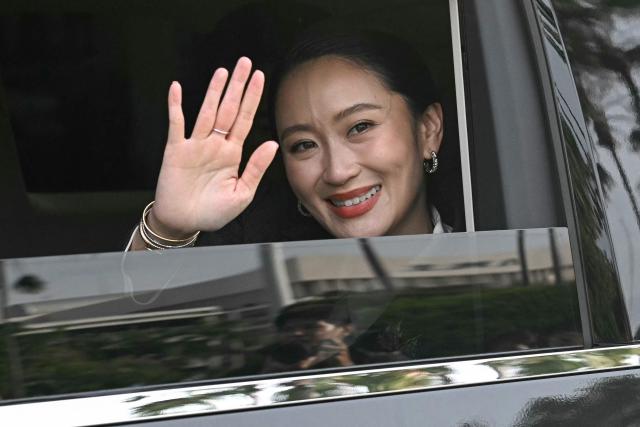 (FILES) Thailand's sacked prime minister Paetongtarn Shinawatra waves from a car as she leaves Government House after her dismissal by the Constitutional Court in Bangkok on August 29, 2025. Thailand's recently removed prime minister Paetongtarn Shinawatra resigned on October 22, 2025 as leader of the party founded by her father, ex-premier Thaksin, signaling the potential end of the family's decades-long political dynasty. (Photo by Lillian SUWANRUMPHA / AFP)